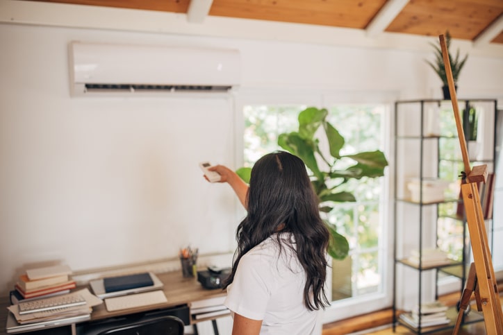 Woman adjusting air con thermostat